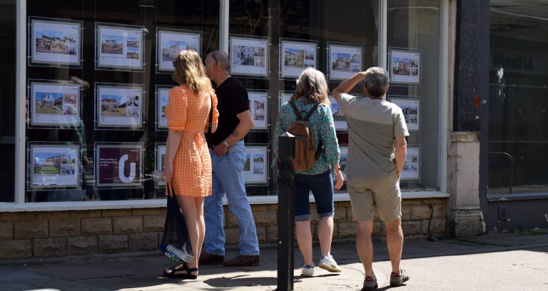 a group of people looking at an estate agents window