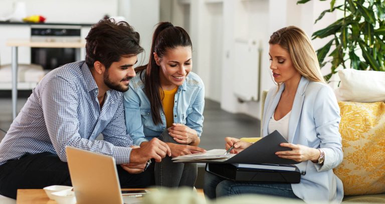 A couple looking at some documents being shown by a business woman