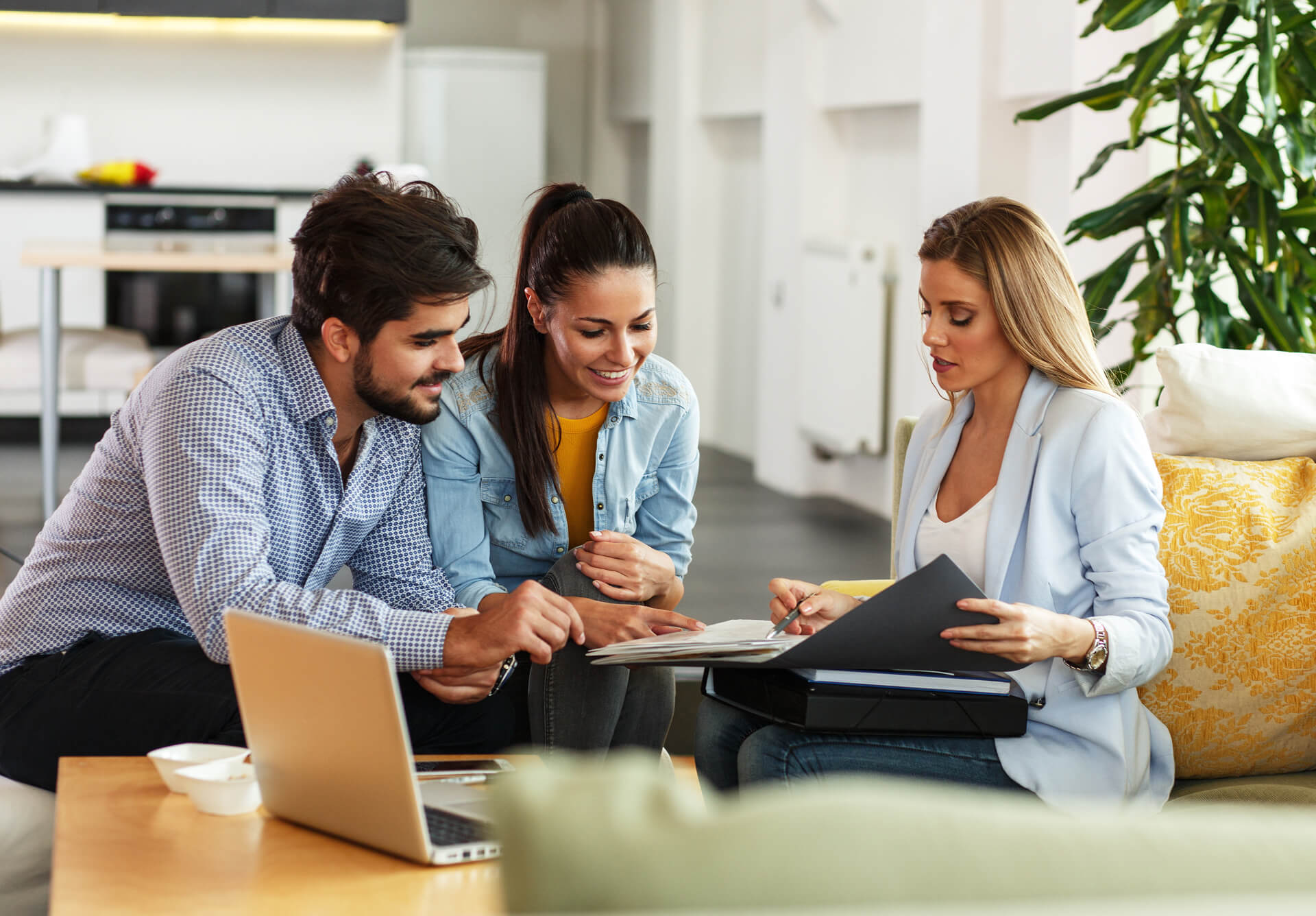 A couple looking at some documents being shown by a business woman