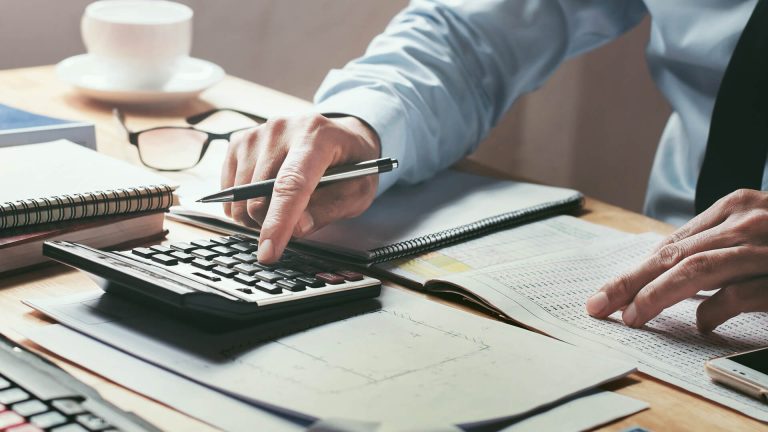 A Businessman working on desk office using a calculator